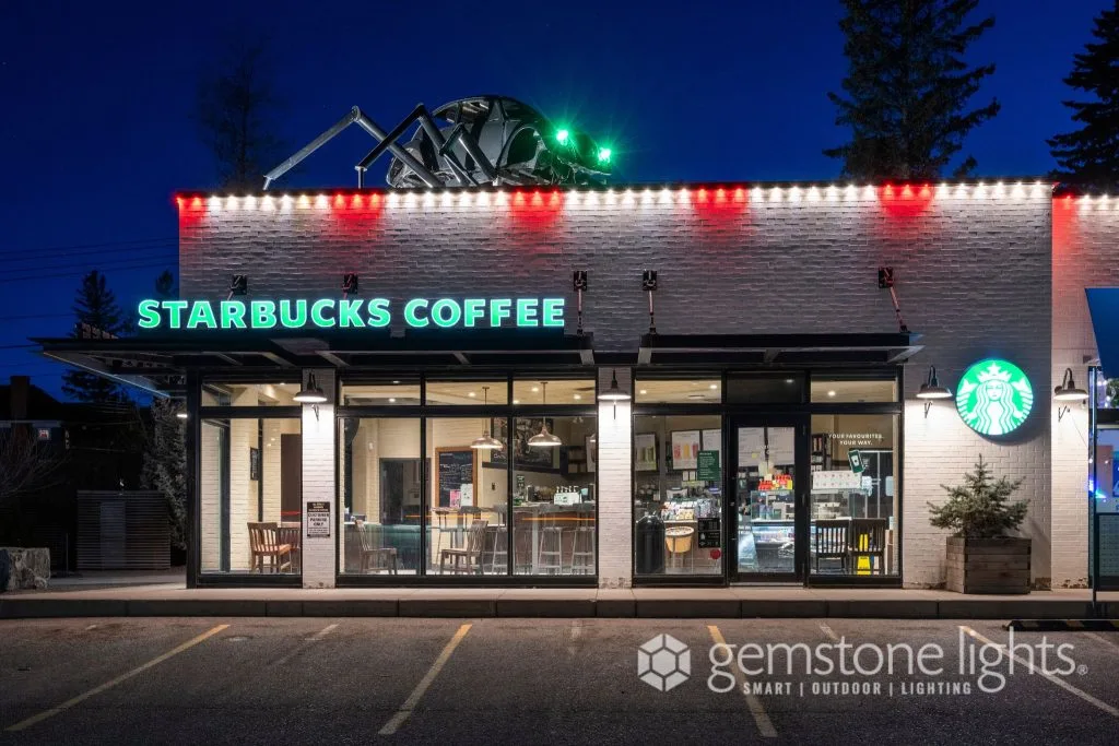 A brightly lit Starbucks storefront stands against a twilight sky, inviting customers inside