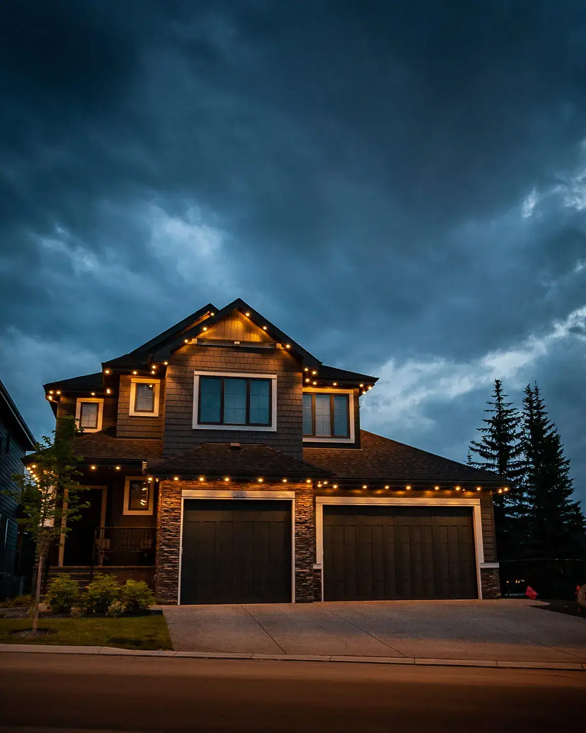 A beautifully lit house stands under a dark, cloudy sky