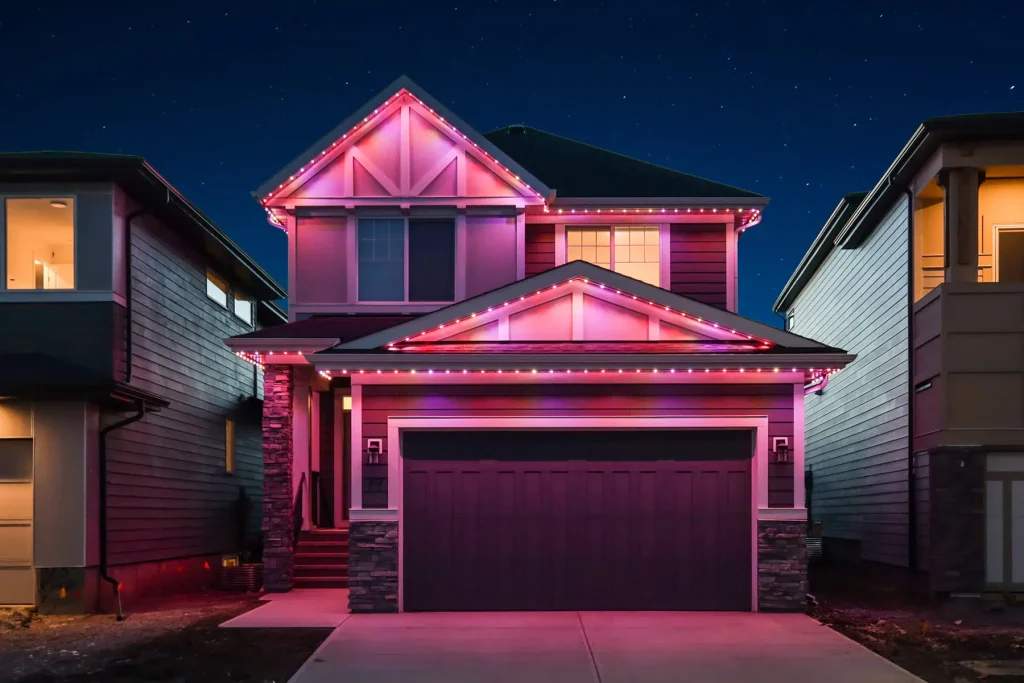 A brightly lit house displays vibrant pink lights against a night sky