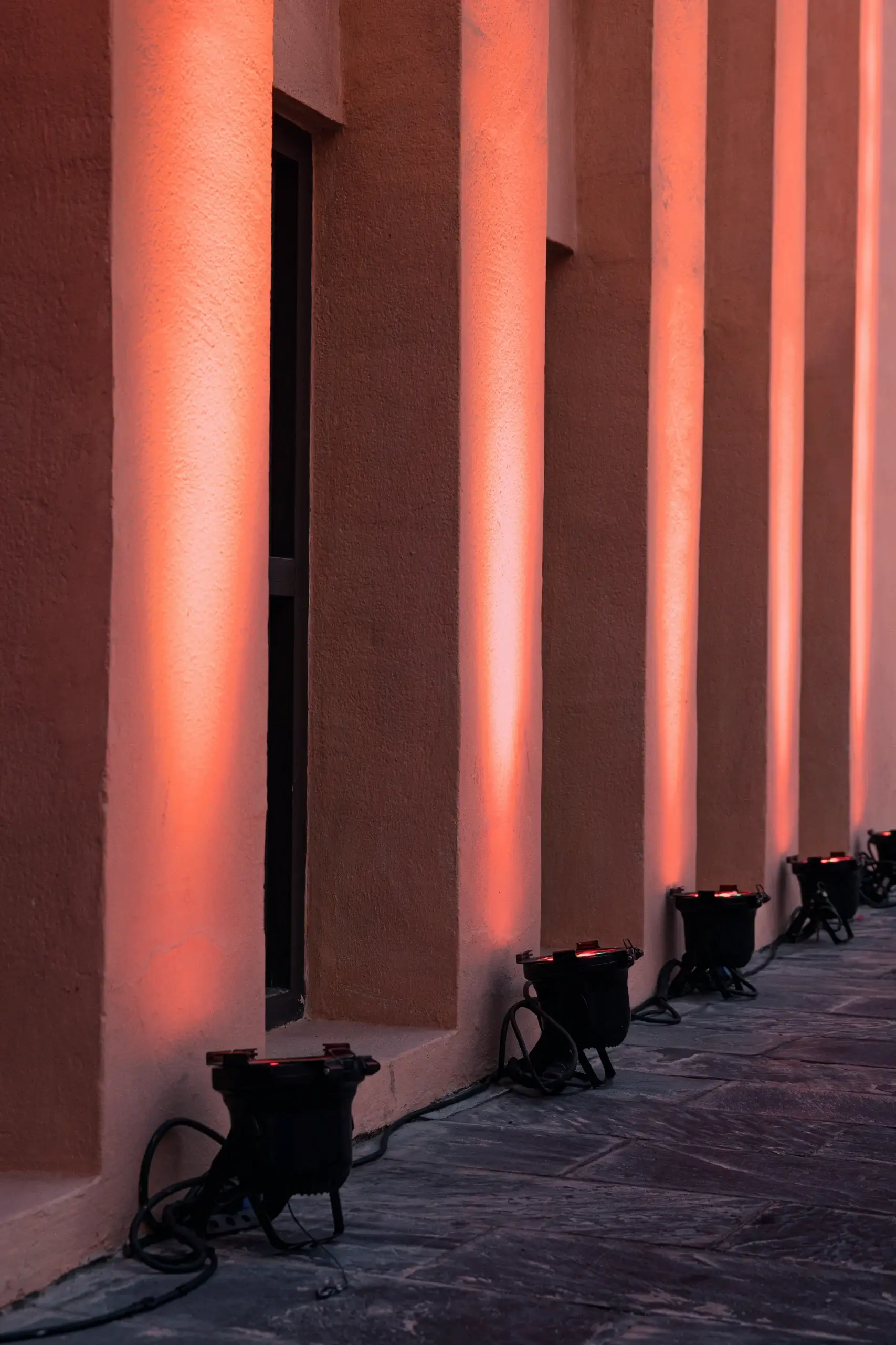 Soft orange light highlights vertical columns against a muted wall