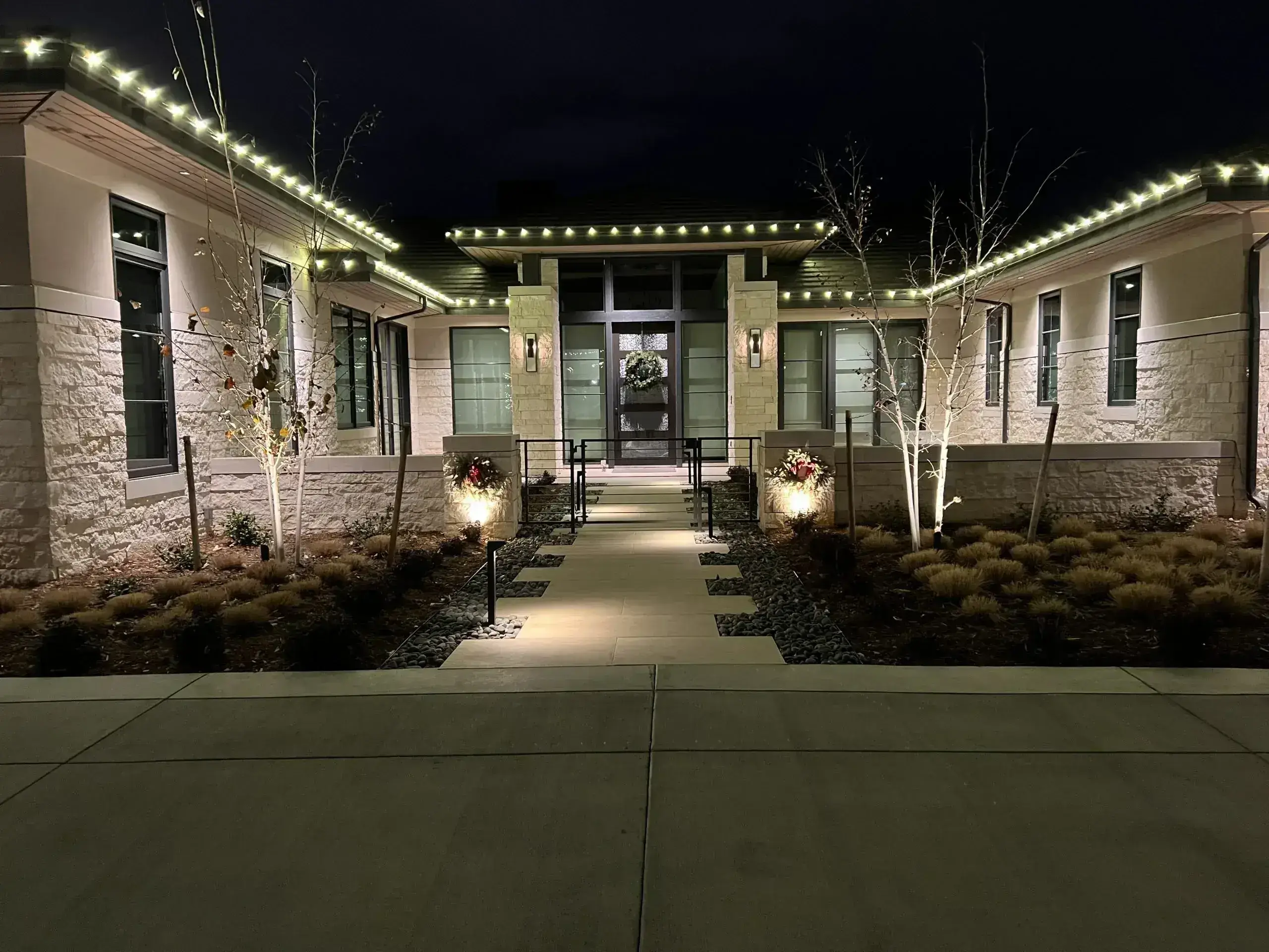 A beautifully lit modern home entrance glows warmly at night