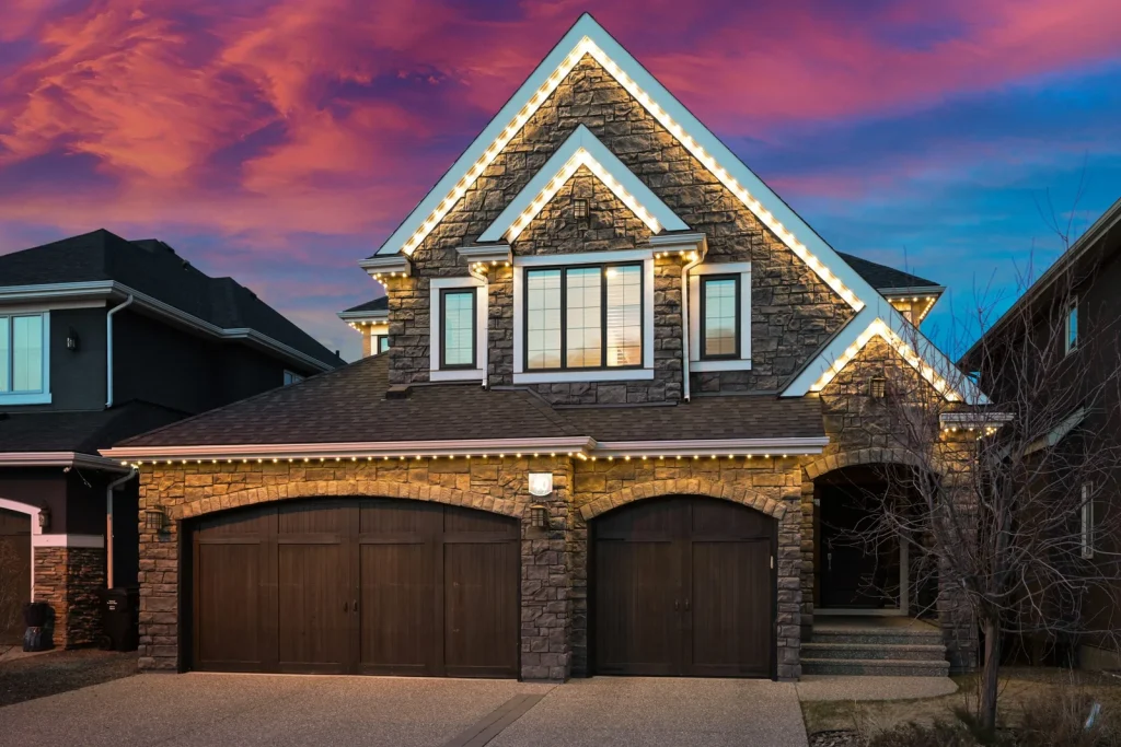 Permanent purple roofline lighting on a stone-front home