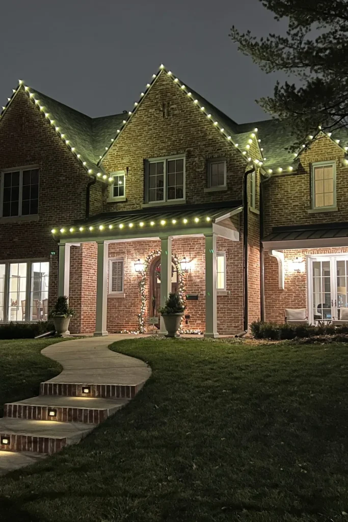 Brick home with warm white Christmas lights along the roofline